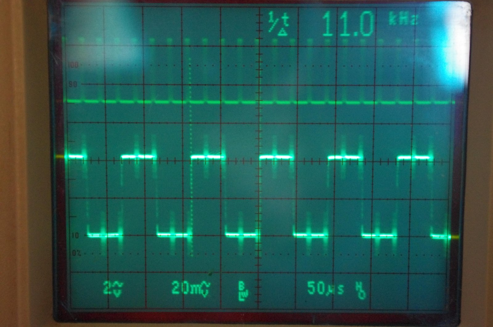 Oscilloscope photograph: a full-scale 11.025 kHz square wave from a TDA1541A with spikes at the edges and on the flat parts, above it the bit-clock burst trace