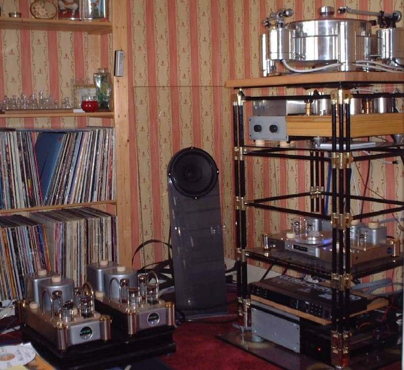 Photograph: the speaker standing between a record shelf, a pair of valve amplifiers and an equipment rack with a turntable