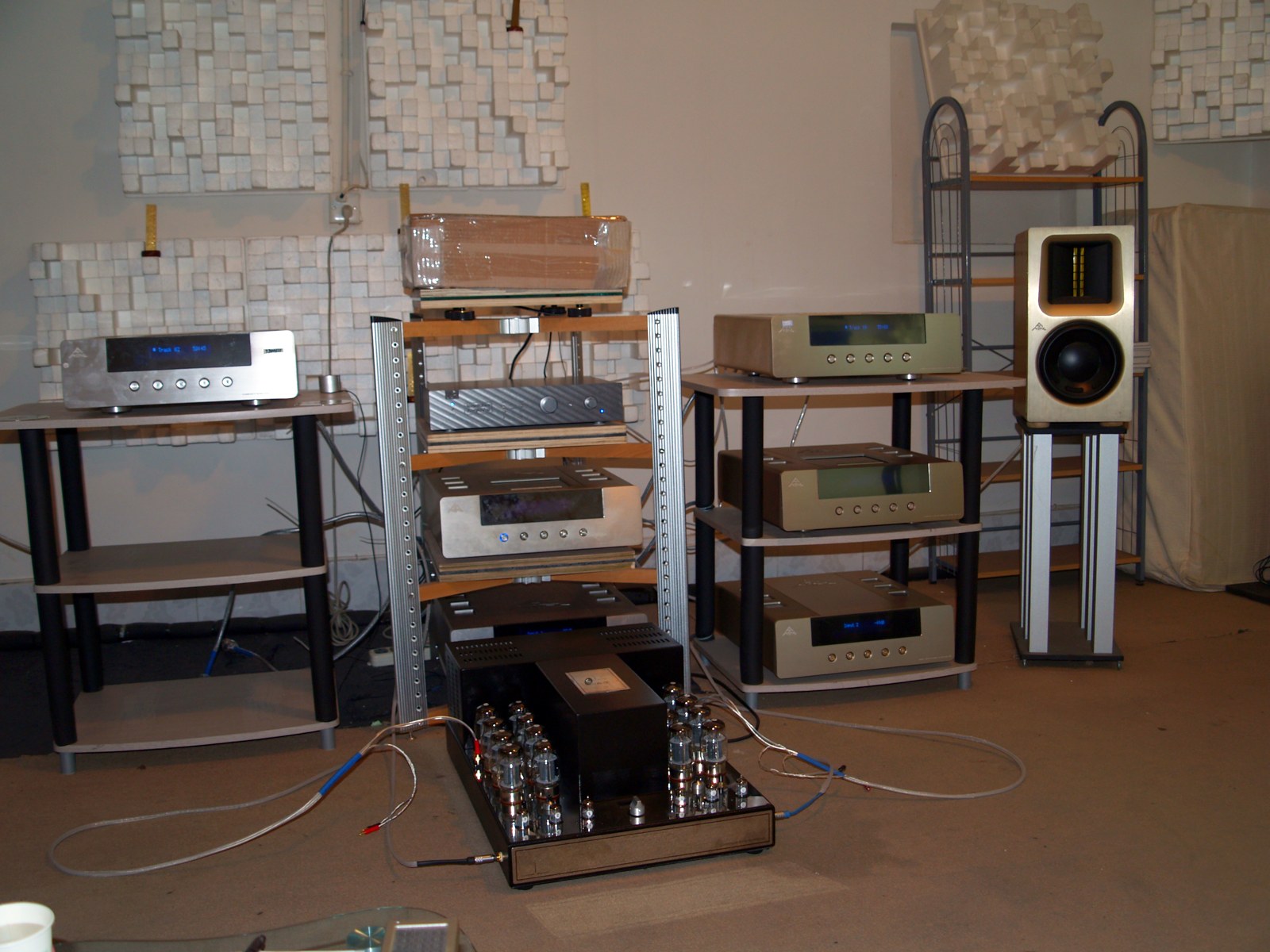 Photograph: the amplifier in a listening room on the floor in front of equipment racks, with a row of output tubes visible